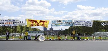 法轮功学员在战神广场上一字排开炼功、发正念，身后是与埃菲尔铁塔遥遥相望的军校（Ecole